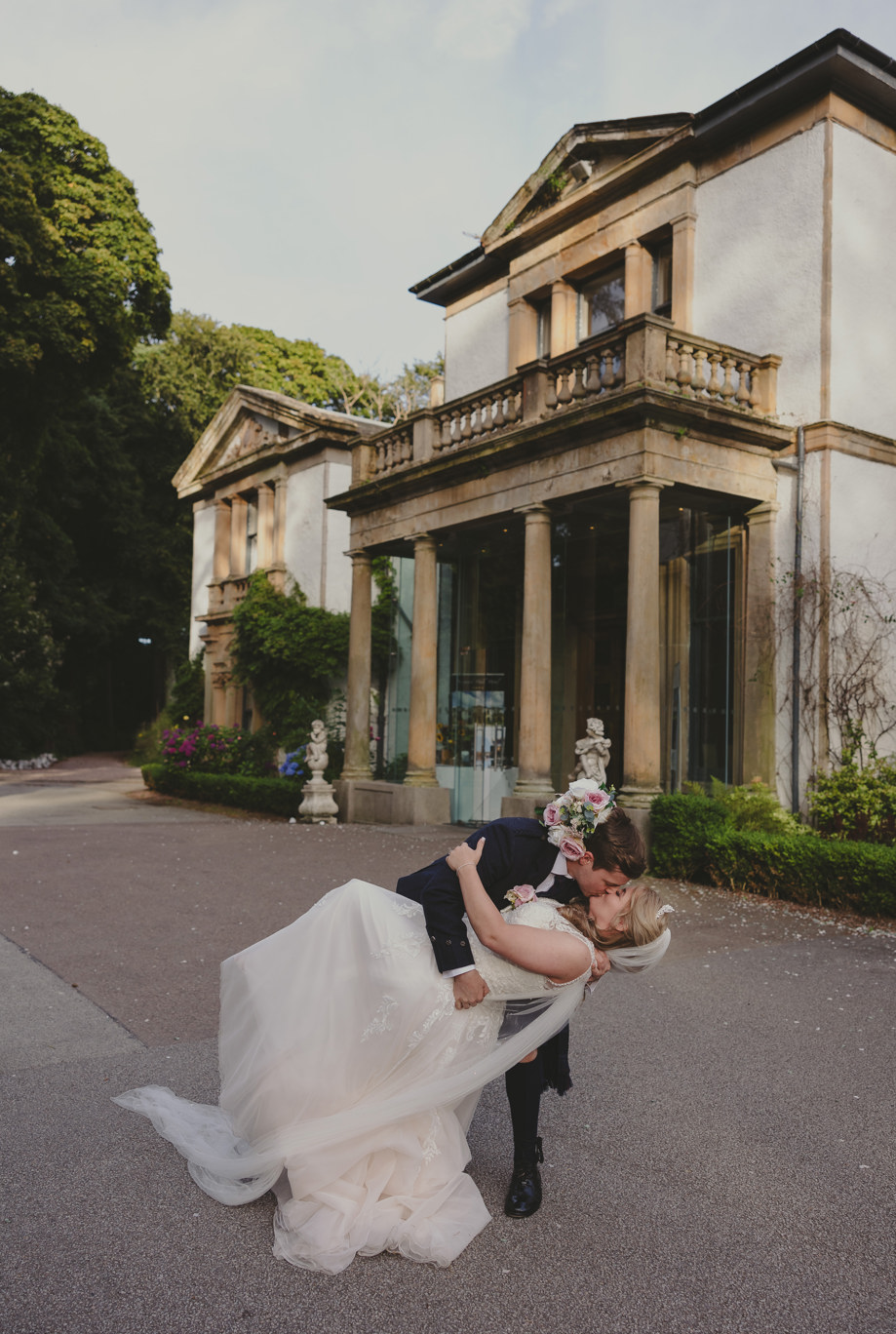 Groom dips his bride for a kiss outside Norwood Hall Hotel